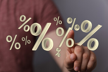 A person's hand touching floating percentage symbols, concept for interest rates, discounts,...