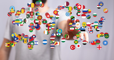 Conceptual image of a person's hand interacting with a collection of flags representing global...