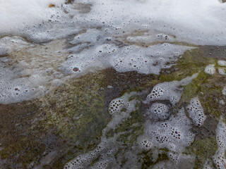 A close up of a rock covered in foam and water