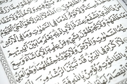 Close-up on the text of the Holy Qur'an, specifically showing Ayatul Kursi (The Throne Verse, Surah Al-Baqarah, Ayat 255)