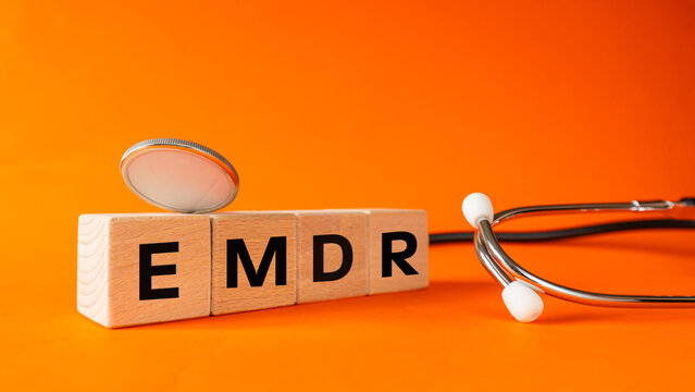 EMDR, Eye Movement Desensitization and Reprocessing. The concept of mental health, the method of treating trauma, PTSD, anxiety disorders, depression, and addiction. The emdr symbol on wooden blocks. 