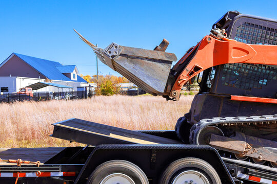 Excavator unloading materials on flatbed trailer at construction site