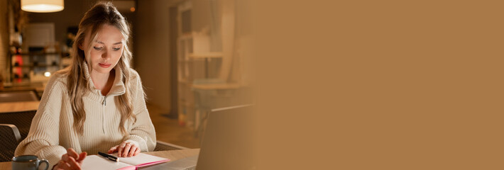 Beautiful student writing notes working studying at night, sitting at table, focusing on work. Preparing for exam