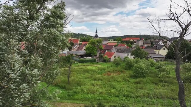 Drone footage rising through trees with a downward tilt, revealing Dorndorf near Laucha, Germany. Scenic aerial view of the countryside in Burgenland district, Saxony-Anhalt.