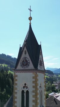 church steeple detail in austria near brenner pass scenic small town in the alps with mountain background river train tracks alpine village christian cross top colorful white drone footage scene 