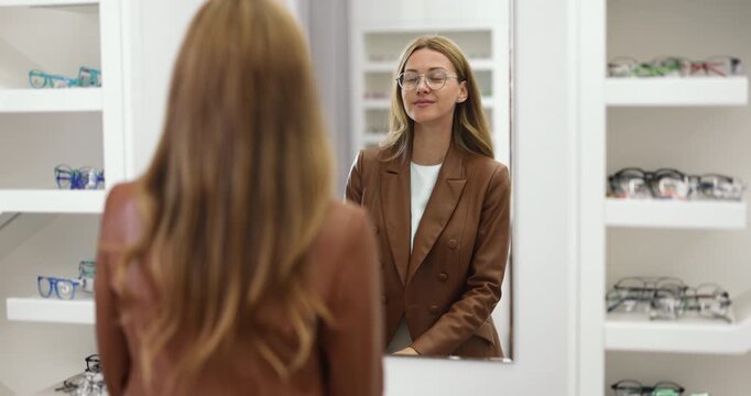 Elegant woman trying eyeglasses in optical boutique