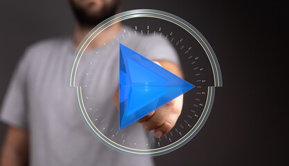 Close up shot of a man pointing to a blue play button representing video or digital media, concept...