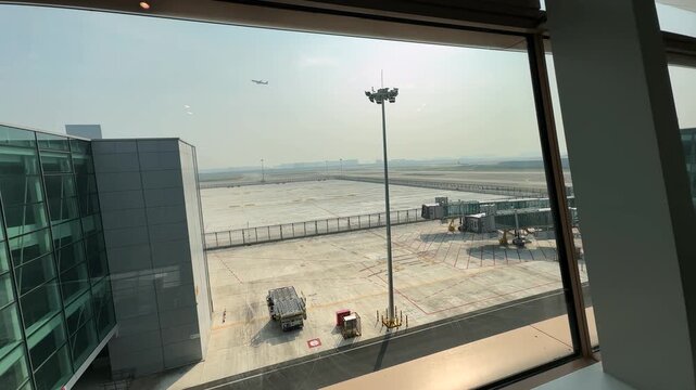 Passenger's perspective from the airport terminal window, watching a commercial plane take off into a clear summer sky. Jet lifting off the runway. 4k footage