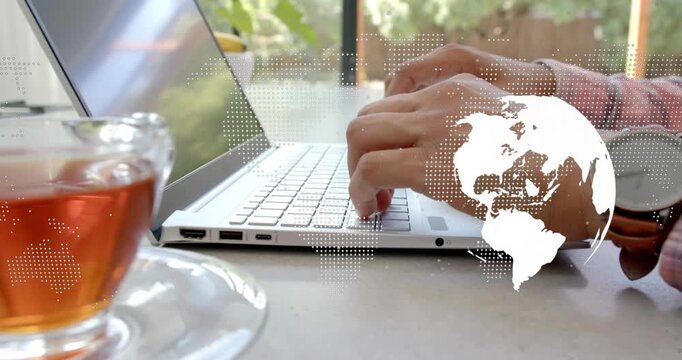 Man typing on laptop by window, keystrokes starting tech globe drifting over keys for work
