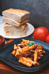 Fresh Penne Pasta with Tomato Sauce and Basil on Black Plate