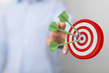 Hand pointing towards a dartboard with darts successfully hitting the center. A symbol of goal achievement, focus, and winning in business or li