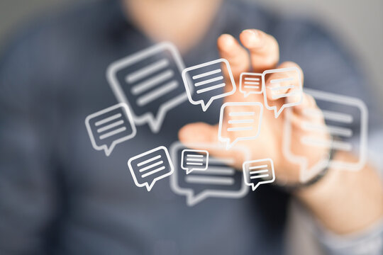 Abstract image showing hand reaching towards speech bubble icons, representing communication and social media. Concepts of digital interaction a