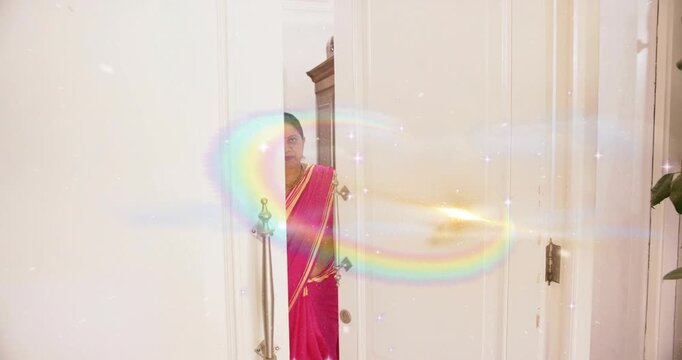 Woman in sari stepping through doorway, gold flash sparking animated rings revealing home decor