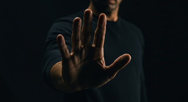 Urgent stop gesture from a man in dark clothing, conveying a powerful message of denial or boundary setting.