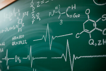 Medical formulas and heart rate graphs drawn with chalk on classroom chalkboard