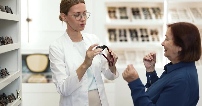 Optician helping to client with sunglasses selection in eyewear store