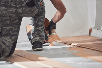 Professional handyman installing laminate flooring in a new apartment.