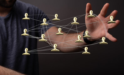 Image of hand holding a network of connected human figures, representing the concept of...