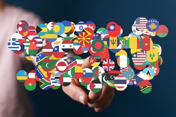 A hand touching a collection of flags representing global unity, digital connection, and...