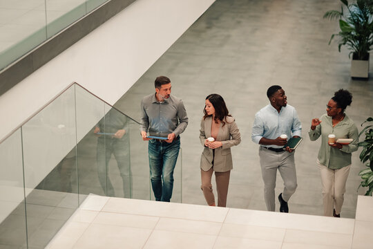 Diverse business people walking and talking on office stairs