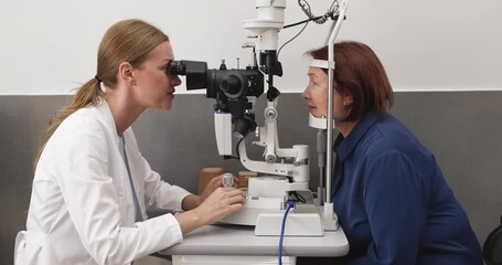 Ophthalmologist examining senior woman with slit lamp