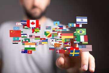 A person's hand pointing towards a collection of global flags, symbolizing international relations,...