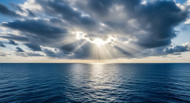 Sunbeams breaking through dramatic clouds over a calm ocean horizon