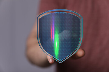 Close-up of a hand holding a glowing digital shield, symbolizing protection, security, and cybersecurity in a business or technologic