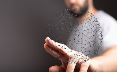 Close-up of a man's hand holding a digital sphere, symbolizing connectivity, innovation and the...