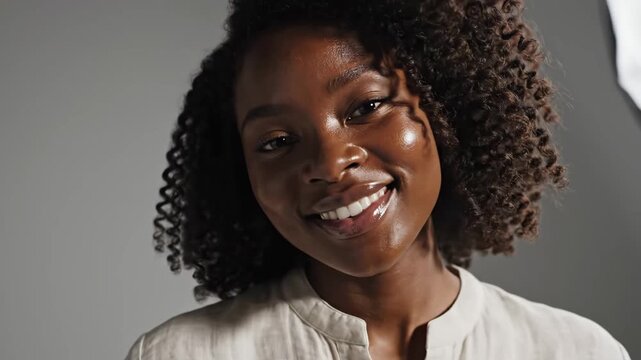 Portrait of Beautiful African American Woman Smiling - This portrait captures a stunning African American woman with dark skin and curly hair smiling genuinely at the camera.