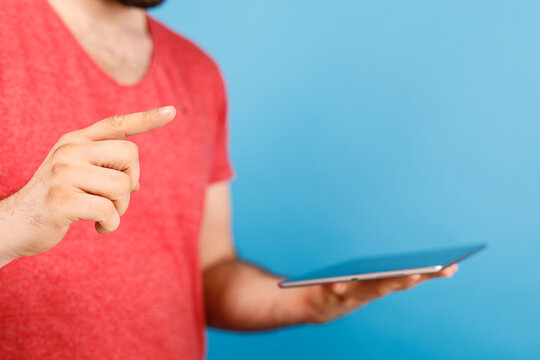 A man in a red shirt points to a tablet, indicating information or a digital interface. Demonstrating a digital connection or concept, great for