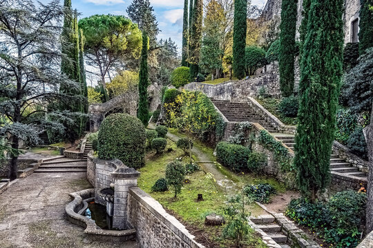 Terraced gardens of Jardins de la Francesa with stone stairways, cypress trees, sculpted hedges, and an ancient fountain creating a serene Mediterranean oasis. Girona, Spain