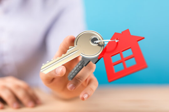 Person holding keys with a house-shaped keyring, symbolizing homeownership, real estate, and property investment. Perfect for mortgage ads, hous