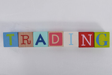 Colorful wooden blocks spelling 'TRADING' against a white background. A visual representation of finance, investment, and the stock market.