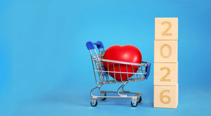 Bright blue background features a shopping cart holding a vibrant red heart, symbolizing love and happiness as we welcome the new year 2026