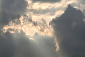 An evening dramatic golden hour sky background with clouds and soft sun rays breaking through.