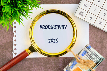 A magnifying glass focuses on the word productivity for the year 2026, surrounded by money, a...