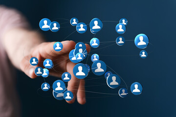 Hand reaching towards a digital network of user icons, symbolizing connection and global communication. Modern technology for social networking