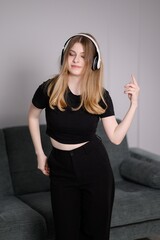 Young woman enjoys music while dancing in living room. Carefree, relaxed student enjoys weekend, spending free time alone at home, listening to music, relaxing.