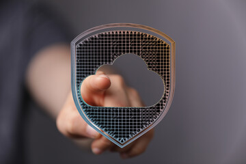 Concept of data security and cloud protection. A hand reaching for a digital shield with a cloud shape, represe
