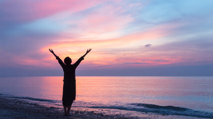 Fototapeta premium Silhouette of woman embracing sunrise on a serene beach with a colorful sky