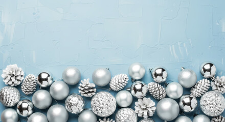 ELEGANT SILVER CHRISTMAS ORNAMENTS AND PINE CONES ON ICY BLUE TEXTURED BACKGROUND WITH COPY SPACE