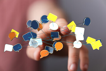 Abstract network of speech bubbles connected by lines held by a person's hand, representing online...