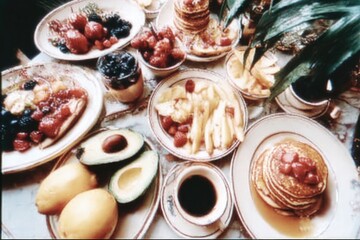 Colorful spread of breakfast featuring pancakes, fruits, and beverages on table