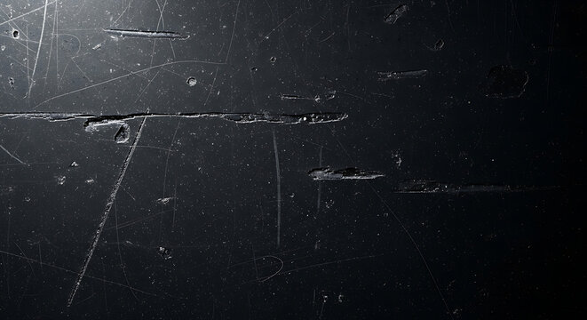 Close up of a dark scratched surface with visible damage and imperfections creating a textured look