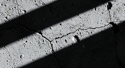 Close up of cracked concrete surface with diagonal shadow creating contrast and texture detail