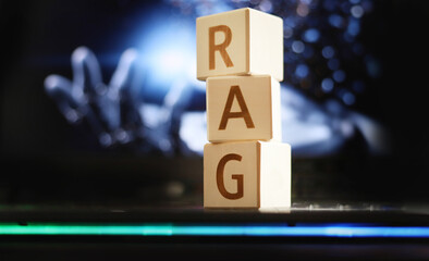 Stacked wooden blocks show the letters RAG against a blurred backdrop of a robotic hand and digital patterns, symbolizing the integration of artificial intelligence and technology