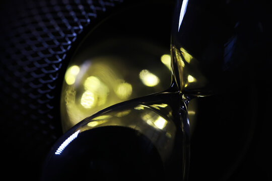 Abstract Hourglass with Vibrant Yellow Light Reflections Against Mesh Background