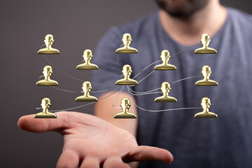 Conceptual image of a hand holding a gold human network. Illustrates networking, teamwork, and...