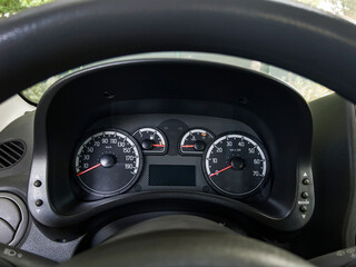 Closeup of a modern car dashboard showing speedometer tachometer fuel and temperature gauges with clear analog design and black background.